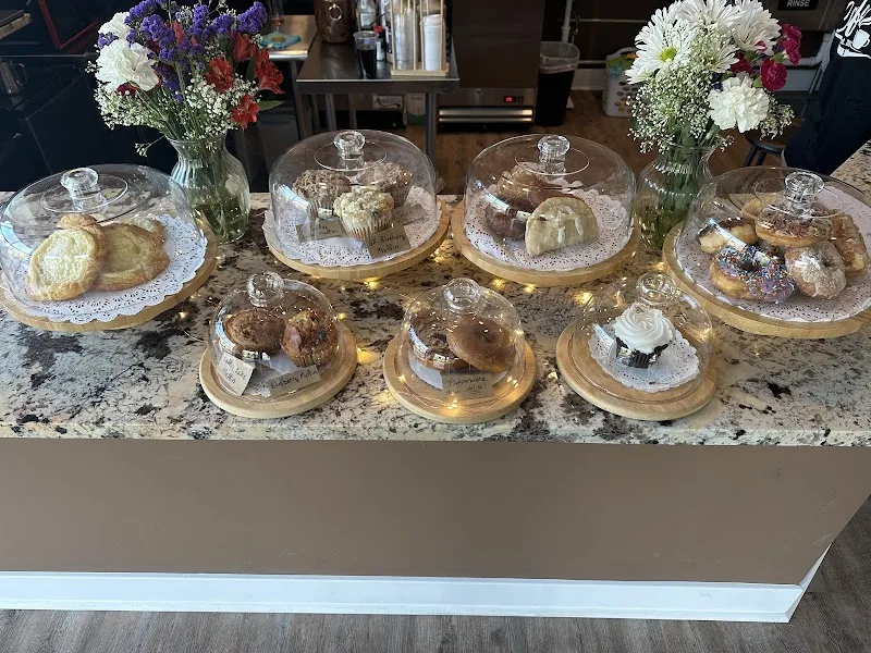 Assortment of freshly baked pastries under glass domes at the café counter